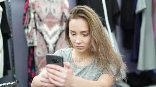 Chica bonita tomando selfie en una tienda de ropa 4K . — Vídeos de Stock