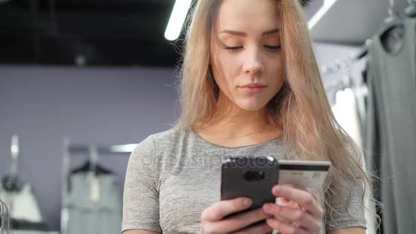 Mulher segurando um cartão de crédito e usando telefone celular para compras on-line. 4K — Vídeo de Stock