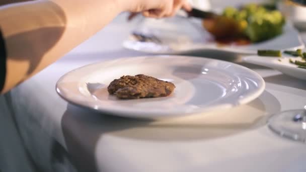 Zbliżenie na ręce womans cięcia wołowiny przy stole w restauracji 4k — Wideo stockowe