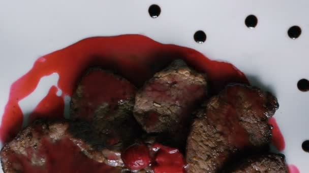 Поворачивая тарелку с мясом и красным соусом на тарелке — стоковое видео