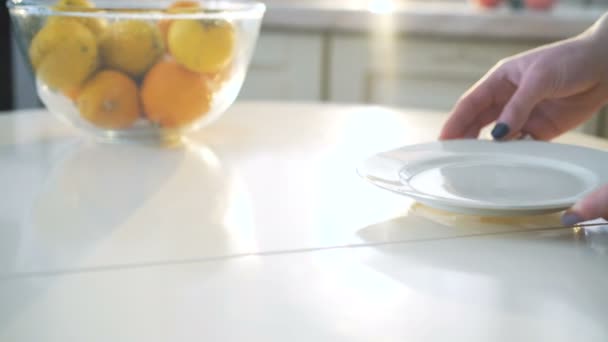 Девушка кладет белую тарелку на стол в 4K — стоковое видео