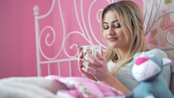 Блестящая блондинка пьет чай в постели в 4K — стоковое видео