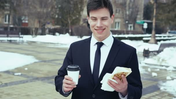 Молодий бізнесмен з кавою і фаст-фудом в руках. 4k — стокове відео