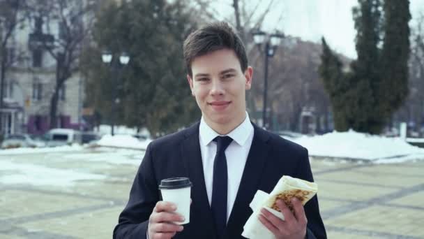 Joven empresario con café y comida rápida en las manos. 4k — Vídeos de Stock