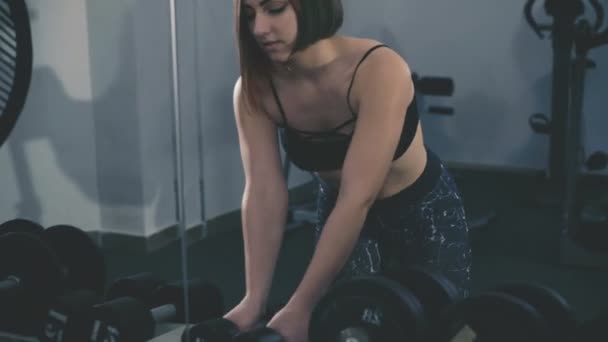 Pretty girl working out in the gym using dumb-bells for muscles and back in 4K — Stock Footage Pretty girl working out in the gym using dumb-bells for muscles and back in 4K Video Clip