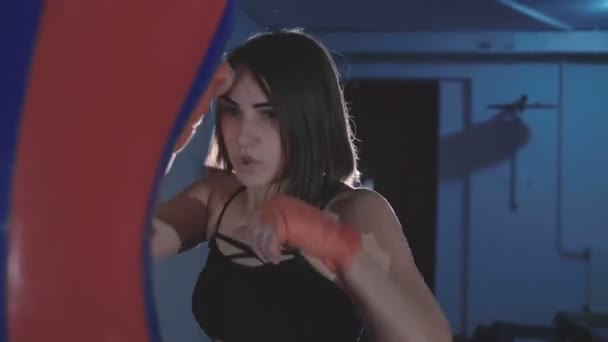 Bastante kickboxing mujer entrenamiento saco de boxeo en estudio deportivo en 4K — Vídeos de Stock