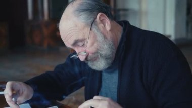 Duygusal yorgun yaşlı adam duman sigara iç geçiriyorum ve 4 k belgeleriyle çalışma