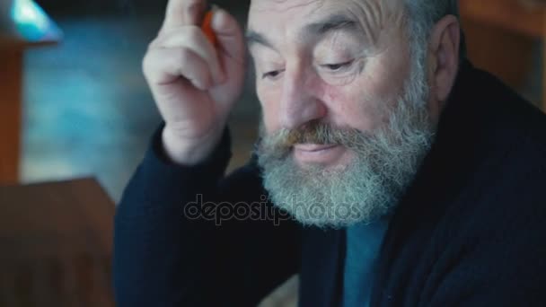 Emocjonalne zmęczony staruszek siedzący, palenia papierosów, myślenie, drapanie ucha 4k — Wideo stockowe