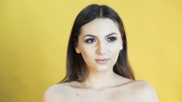 Cute woman with emotion of surprise on yellow background 4K — Stock Video