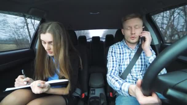 Zakelijke jongen en meisje in de auto, de man die werkt van de telefoon — Stockvideo