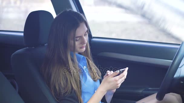 Профиль эмоциональной девушки, сидящей в машине и использующей смартфон — стоковое видео