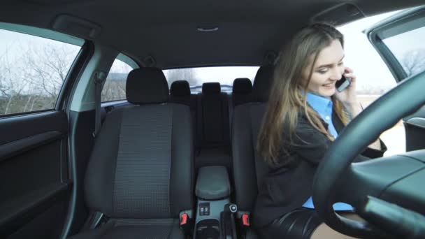 Молодая деловая женщина сидит в машине, разговаривает по телефону и флиртует с 4K — стоковое видео