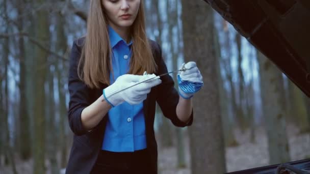 Ładna dziewczyna w rękawiczkach i sprawdzić ilość oleju w samochodzie w 4k — Wideo stockowe