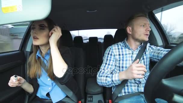 Hombre divertido cantando, bailando, chica se aplica rímel en las pestañas al montar en coche — Vídeo de stock