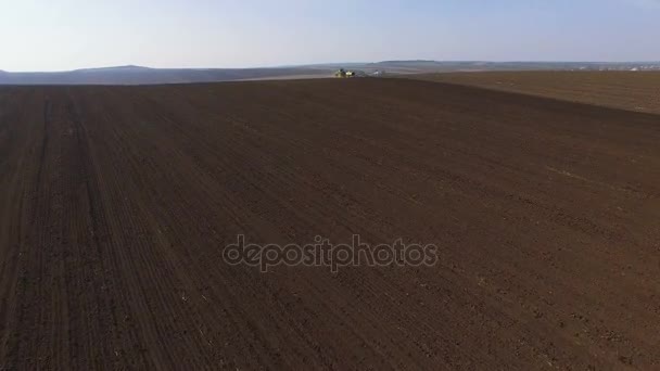Vista aérea de um trator cultivando um campo com solo preto para plantio em 4K — Vídeo de Stock