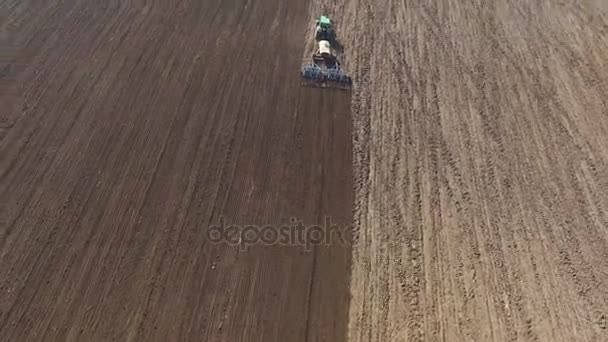 Aerial view of a tractor cultivating a fields with black soil for planting in 4K — Stock Video