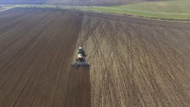 Aerial view of a tractor cultivating a fields with black soil for planting in 4K — Stock Video