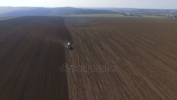 Vista aérea de um trator cultivando um campo com solo preto para plantio em 4K — Vídeo de Stock