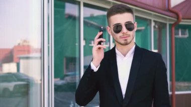 Şık, ciddi yakışıklı erkek güneş gözlüğü 4 k cep telefonu konuşma