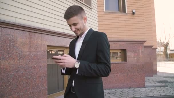 Yürüme ve hareket eden telefon açık havada 4 k kullanarak şık, mutlu bir adam — Stok video