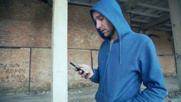 Homme dans la capuche en utilisant smartphone dans les catacombes 4K — Video