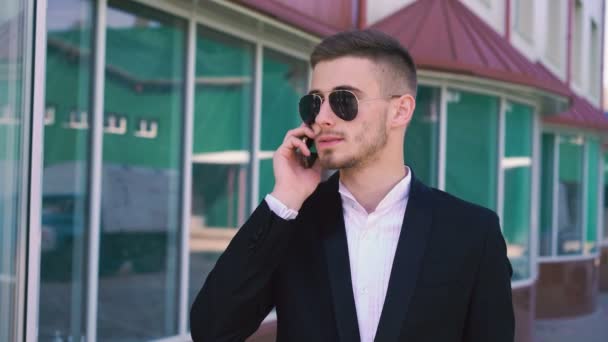 Elegante, hombre guapo serio hablando en el teléfono móvil en gafas de sol 4K — Vídeo de stock