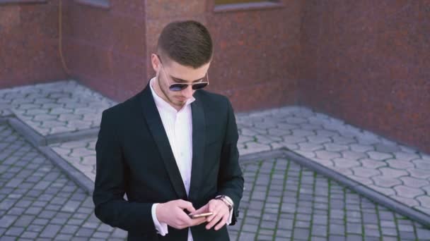 Hombre elegante, serio usando y hablando en el teléfono móvil en gafas de sol 4K — Vídeos de Stock