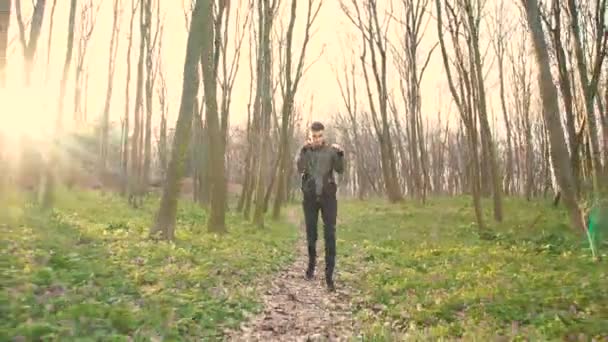 Joven escuchando música en auriculares, correr y hacer ejercicio en el bosque 4K — Vídeos de Stock