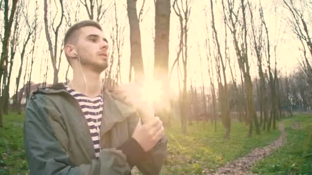 Joven en auriculares ejercitar brazos y manos en el bosque 4K — Vídeos de Stock