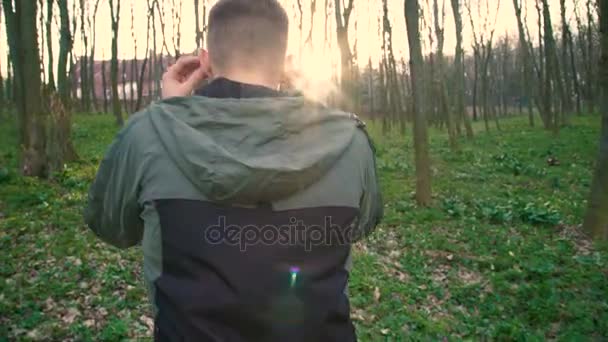 Rückwärtiger Blick des Mannes, der Musik mit Kopfhörern hört, spazieren geht, sich im Wald entspannen 4k — Stockvideo