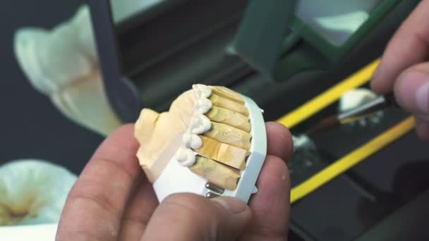 Зубной техник, применяющий керамическую глазурь для литья, изготовленного с помощью станка с ЧПУ — стоковое видео