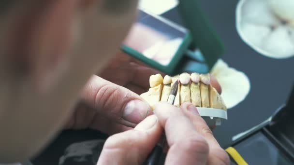 Dental technician applying ceramics glaze to a cast made with CNC dental machine — Stock Video