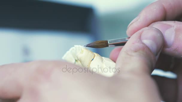 Зубной техник, применяющий керамическую глазурь для литья, изготовленного с помощью станка с ЧПУ — стоковое видео