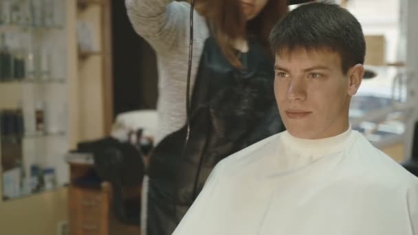 Beau jeune homme obtient un séchage les cheveux dans le salon — Video