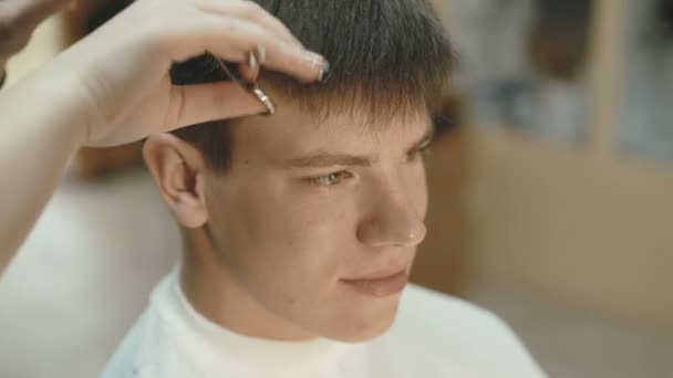 Bonito homem com sorriso no rosto recebe um corte de cabelo no salão — Vídeo de Stock