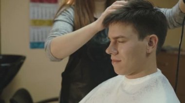 Yakışıklı adam yüzünde gülümsemeyle bir saç kesimi salonda alır.