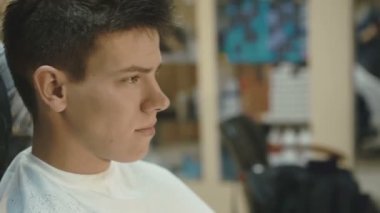 Yakışıklı adam yüzünde gülümsemeyle bir saç kesimi salonda alır.