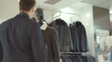 Zarif zengin adam giyim mağazasında giysiler seçmek takım elbiseli