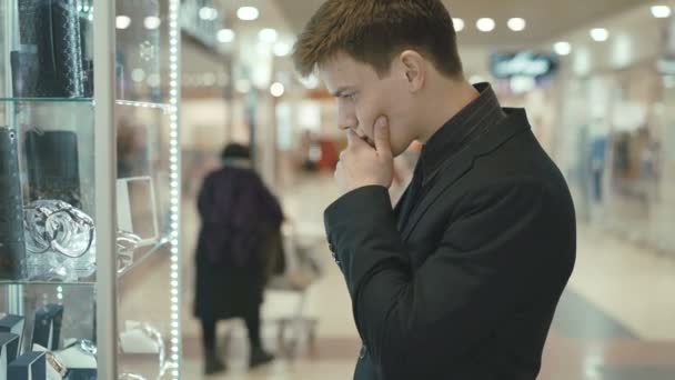 Bel homme regarde vitrine et doutes dans l'achat — Video