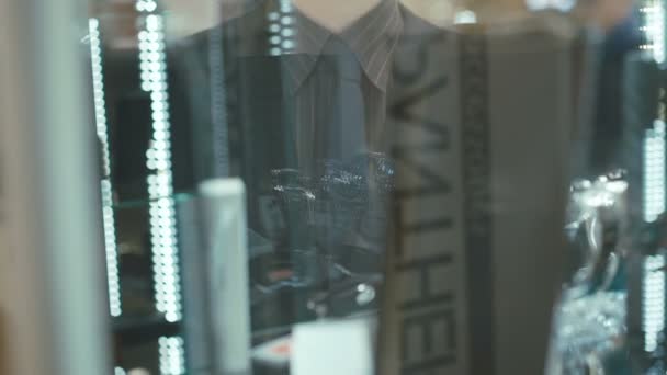 Hombre guapo mira escaparate con relojes para hombre en el centro de la tienda — Vídeos de Stock