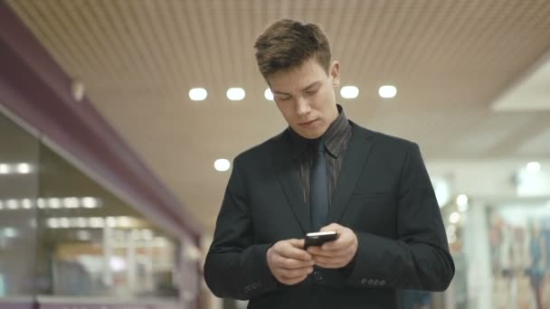 Guapo empresario exitoso haciendo una llamada telefónica en el centro de comercio — Vídeo de stock