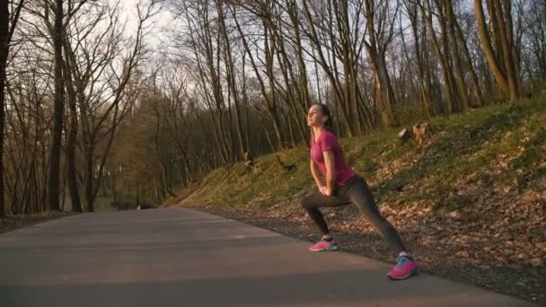 A menina treina alongando-se na natureza no parque 4K — Vídeo de Stock