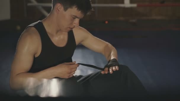 男性のボクサーは、ジムのリング上黒包帯で手をラップします。 — ストック動画