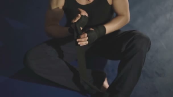 Boxeador masculino envuelve sus manos con vendaje negro en el anillo en el gimnasio — Vídeos de Stock
