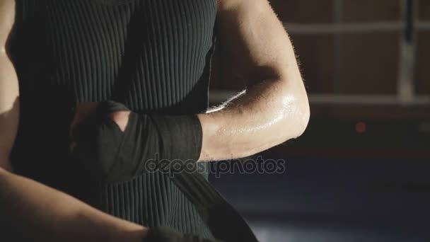 Мужчина-боксер закрывает руки черной повязкой на ринге в спортзале. Медленно. — стоковое видео