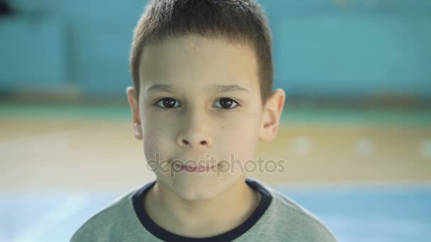 Engraçado menino bonito olhando para trás e rindo da câmera no ginásio 4K — Vídeo de Stock