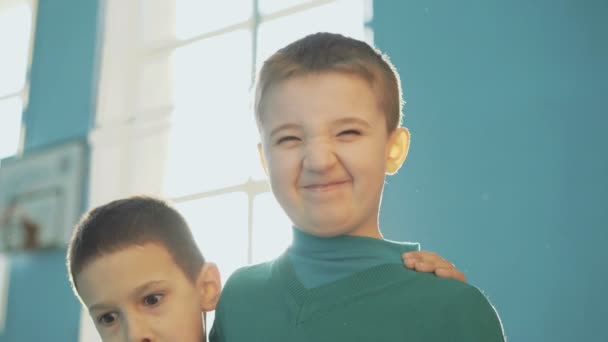 Dos divertidos niños varones abrazándose, haciendo caras y riendo a la cámara en el gimnasio 4K — Vídeos de Stock