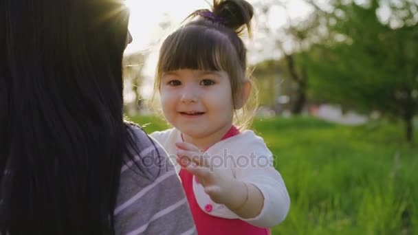 Мила весела маленька дівчинка, обіймаючи матір і сміючись на камеру — стокове відео
