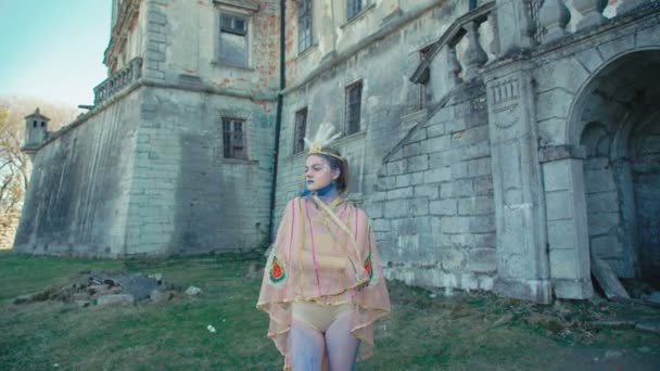 The girl in the image of peahen posing near the ancient castle 4K — Stock Video