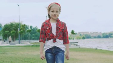 Küçük sarışın kamera için sahilde yürüyor. Yavaş yavaş